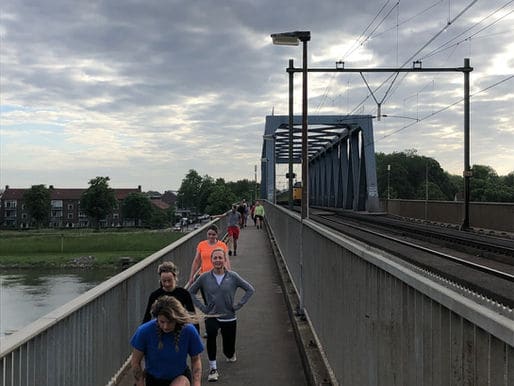 Een groep R.UIT’ers loopt met lunges over het voetpad van de Deventer spoorbrug