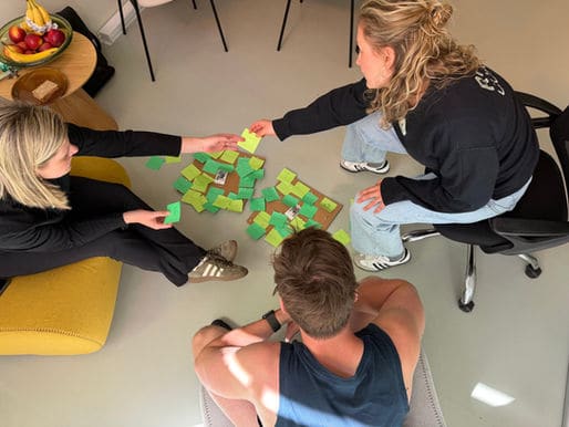 Drie R.UIT’ers zitten op de grond en leggen groene briefjes met zaalnamen op een rij